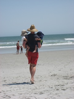 Dad carrying kids on beach